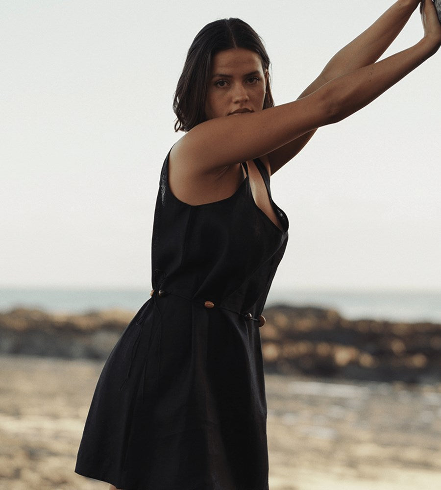Woman in a black dress standing on a beach with a blurred background