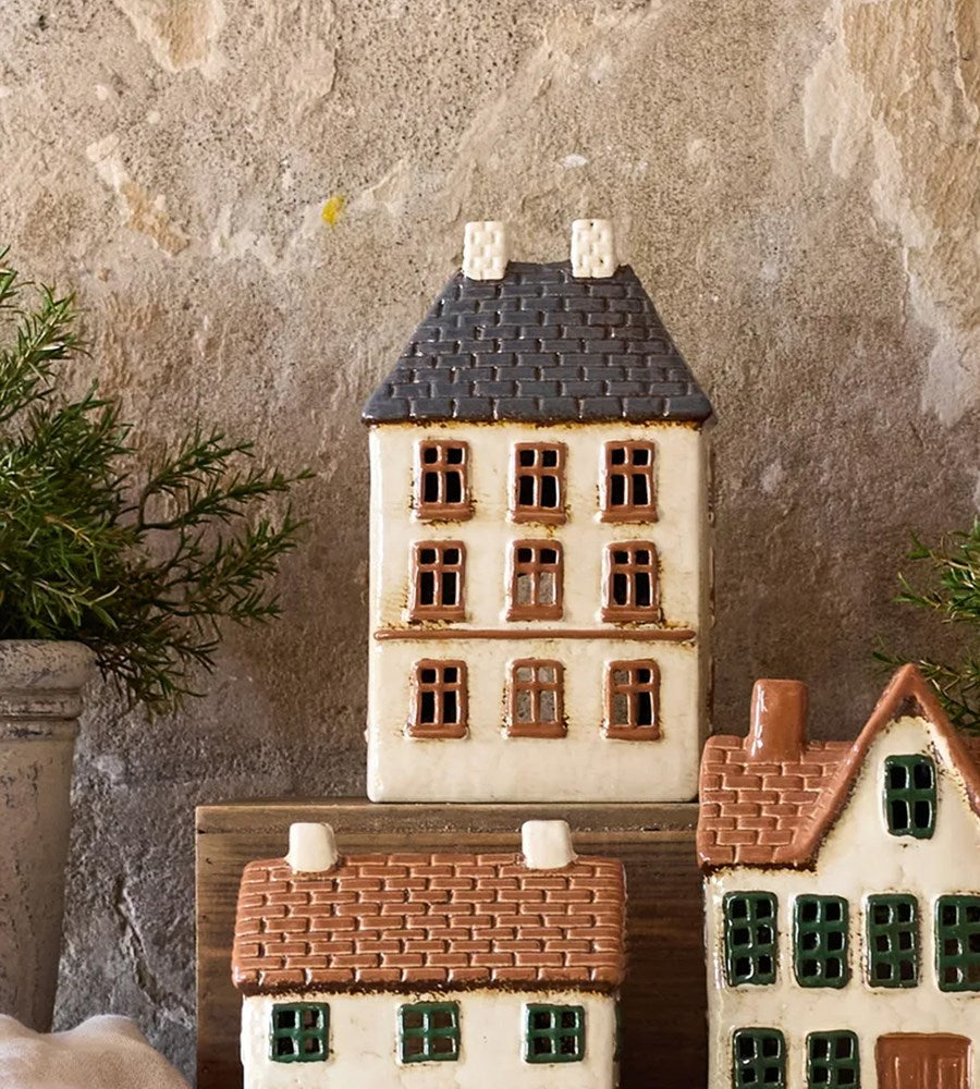 Set of ceramic house models with different roof colors against a textured wall.