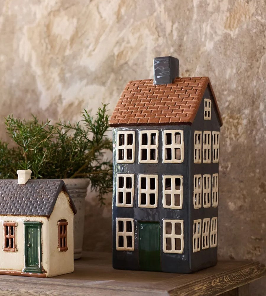 Two ceramic house models on a wooden surface with a textured wall background