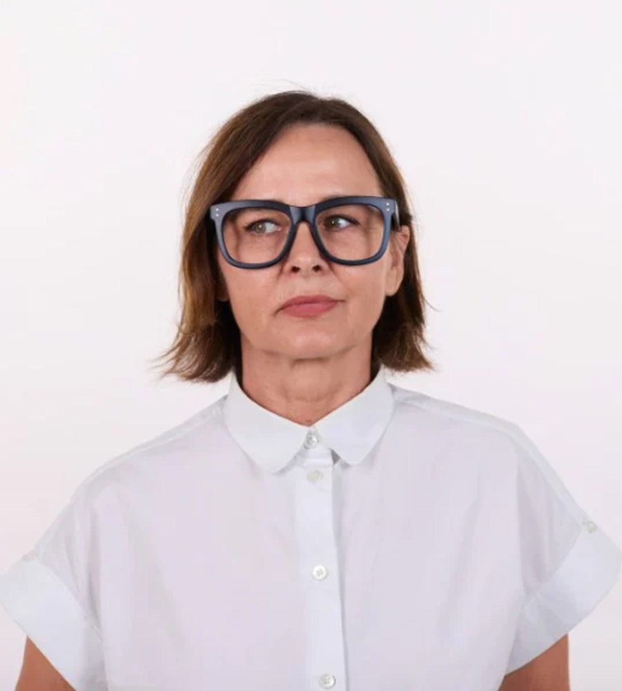 Person wearing a white shirt and large black glasses on a white background