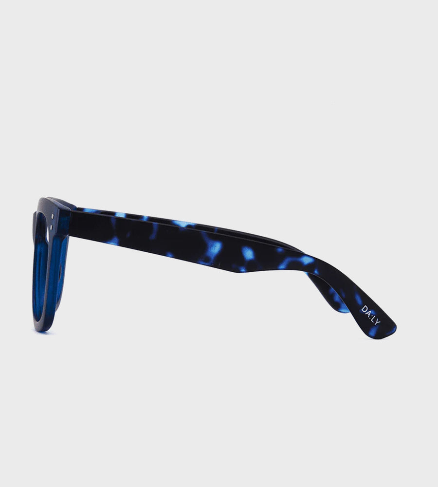 Sunglasses with blue tortoiseshell frame on a light gray background