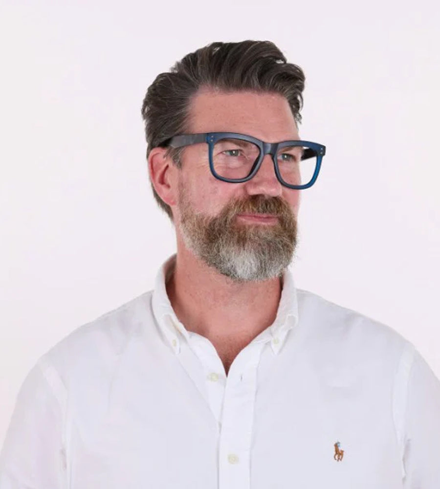 Man wearing blue eyeglasses and a white shirt with a logo on a white background