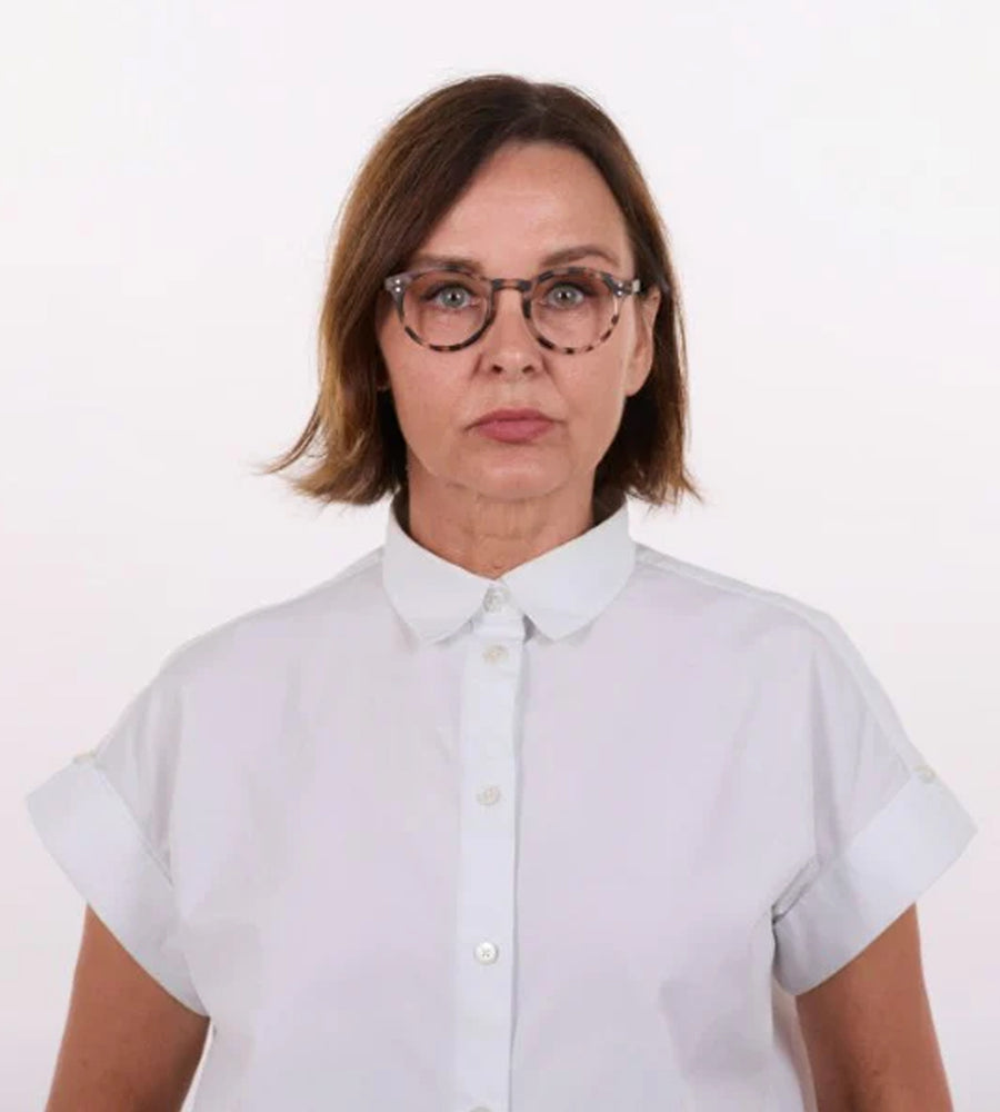 Person wearing a white shirt and glasses on a plain background