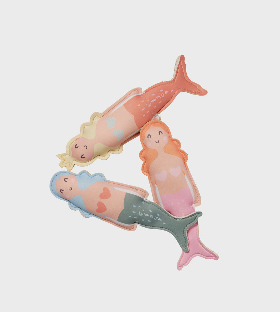 Three mermaid figurines with different colored tails on a light gray background