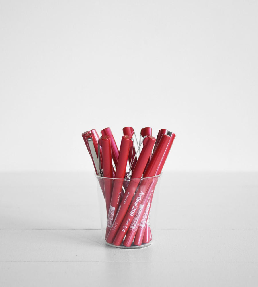 Red markers in a clear glass on a white background