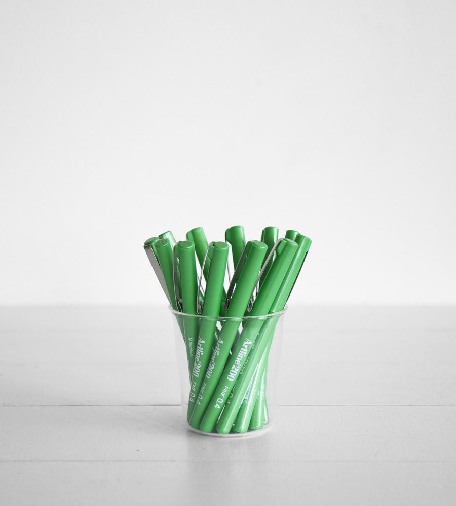 Clear plastic cup filled with green markers on a white background