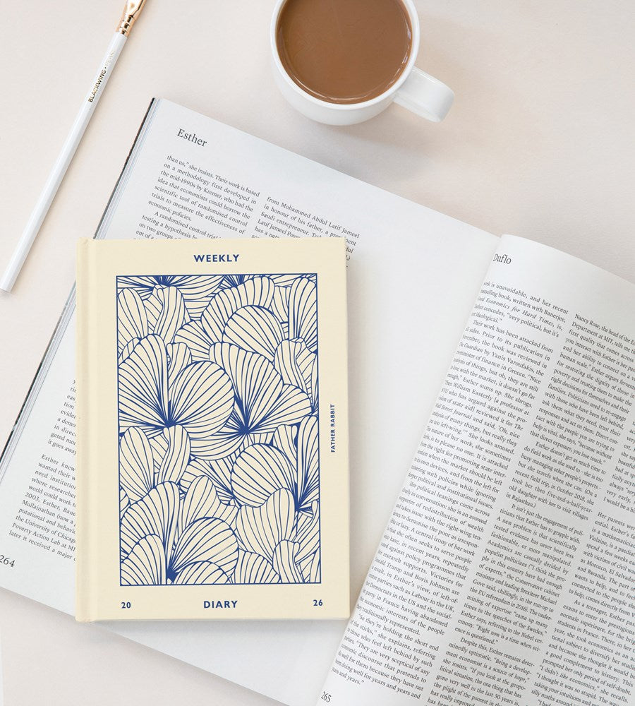 Diary with floral design on a book next to a cup of coffee