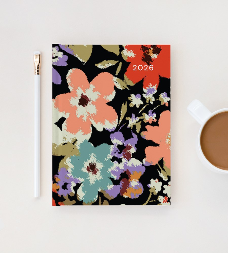 Floral notebook with 2026 on a white surface next to a pen and mug.