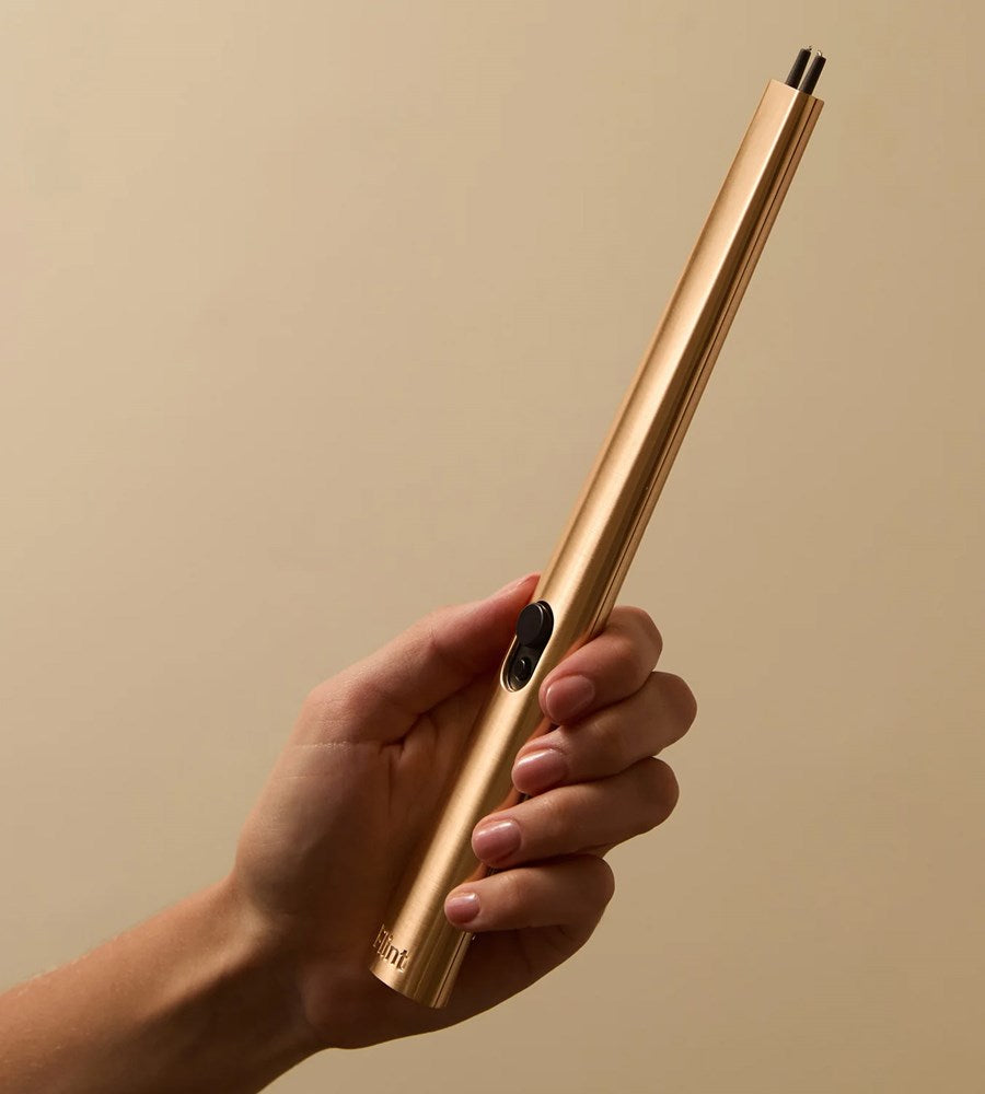 Hand holding a gold pen against a beige background