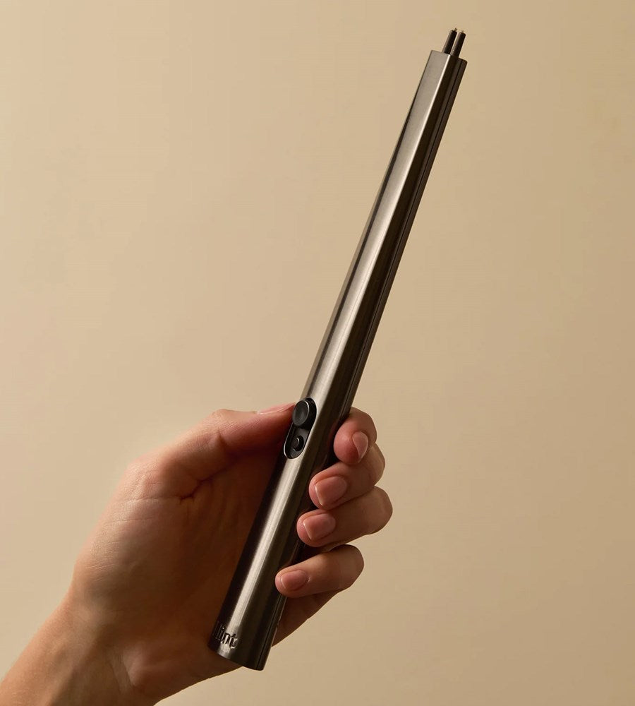 Hand holding a metallic object against a beige background