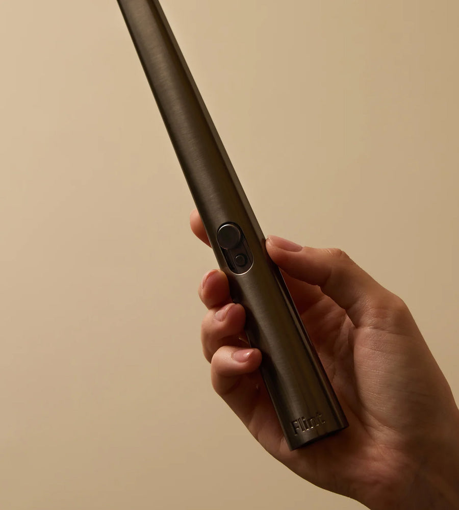 Hand holding a brown electronic device with 'Fuzion' branding against a beige background