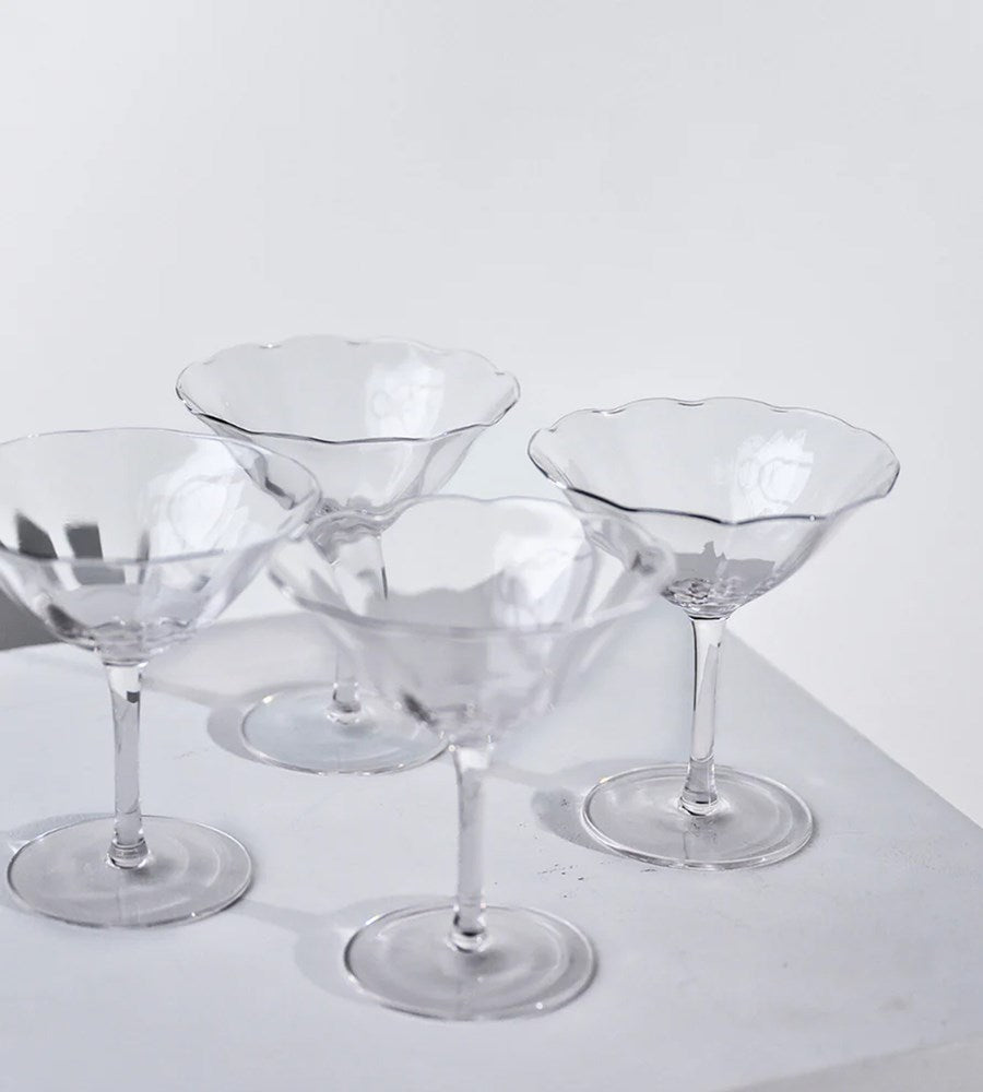 Set of clear glass cocktail glasses on a white surface with a white background
