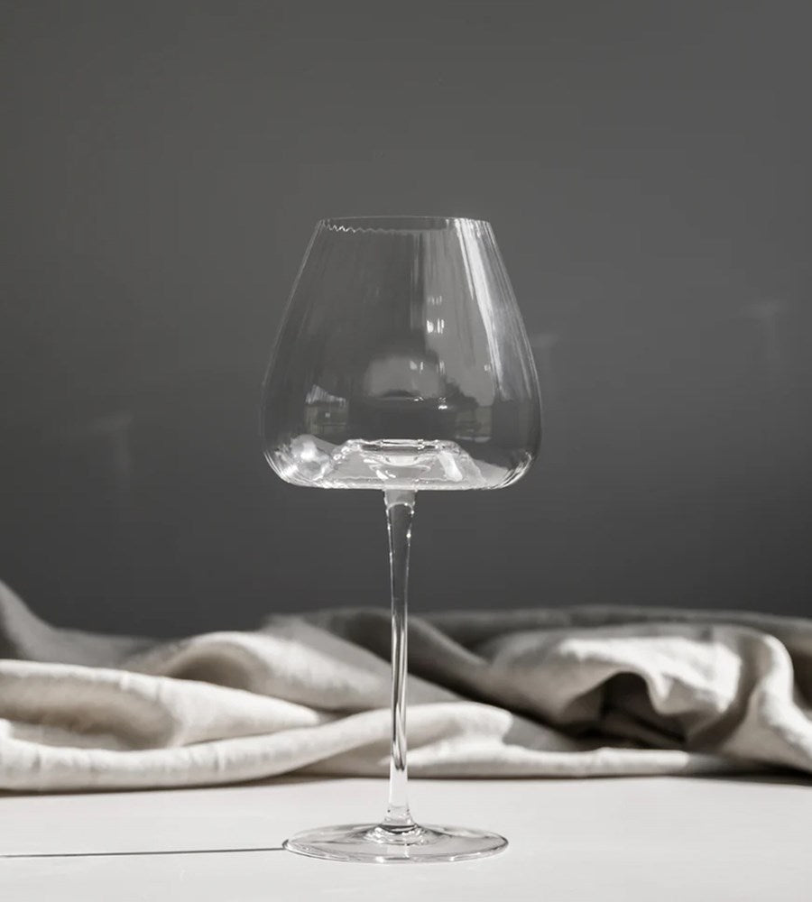 Clear wine glass on a dark surface with a gray cloth