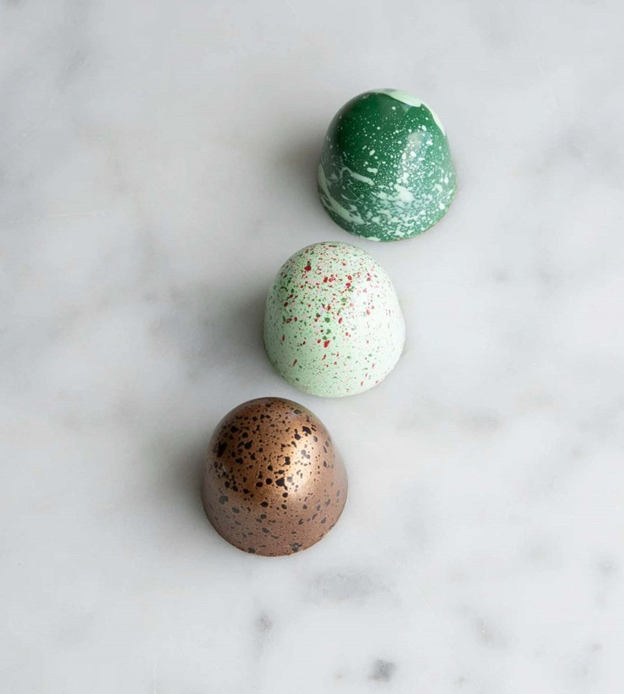Three colorful bath bombs on a marble surface