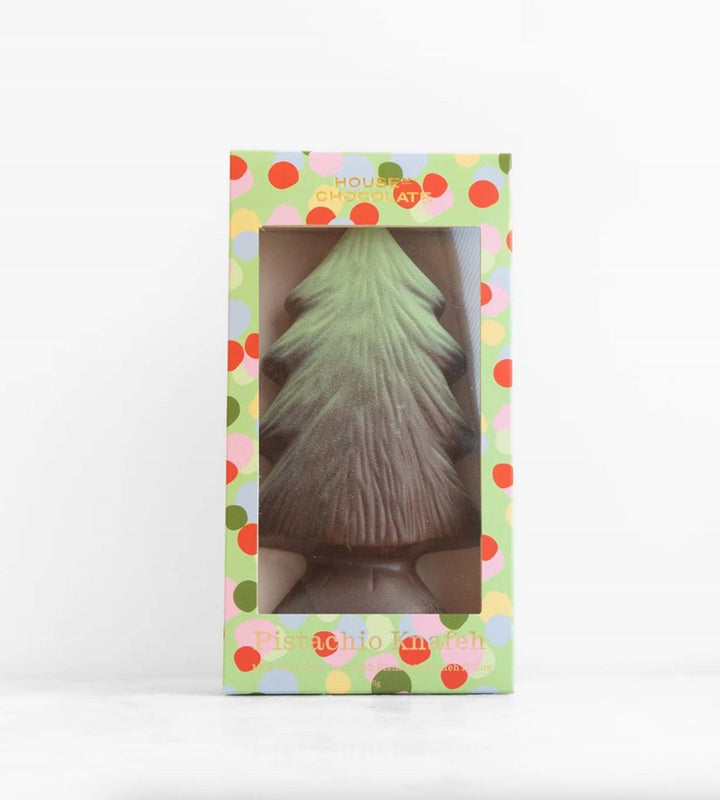 Decorative Christmas tree-shaped candle in a colorful box on a white background