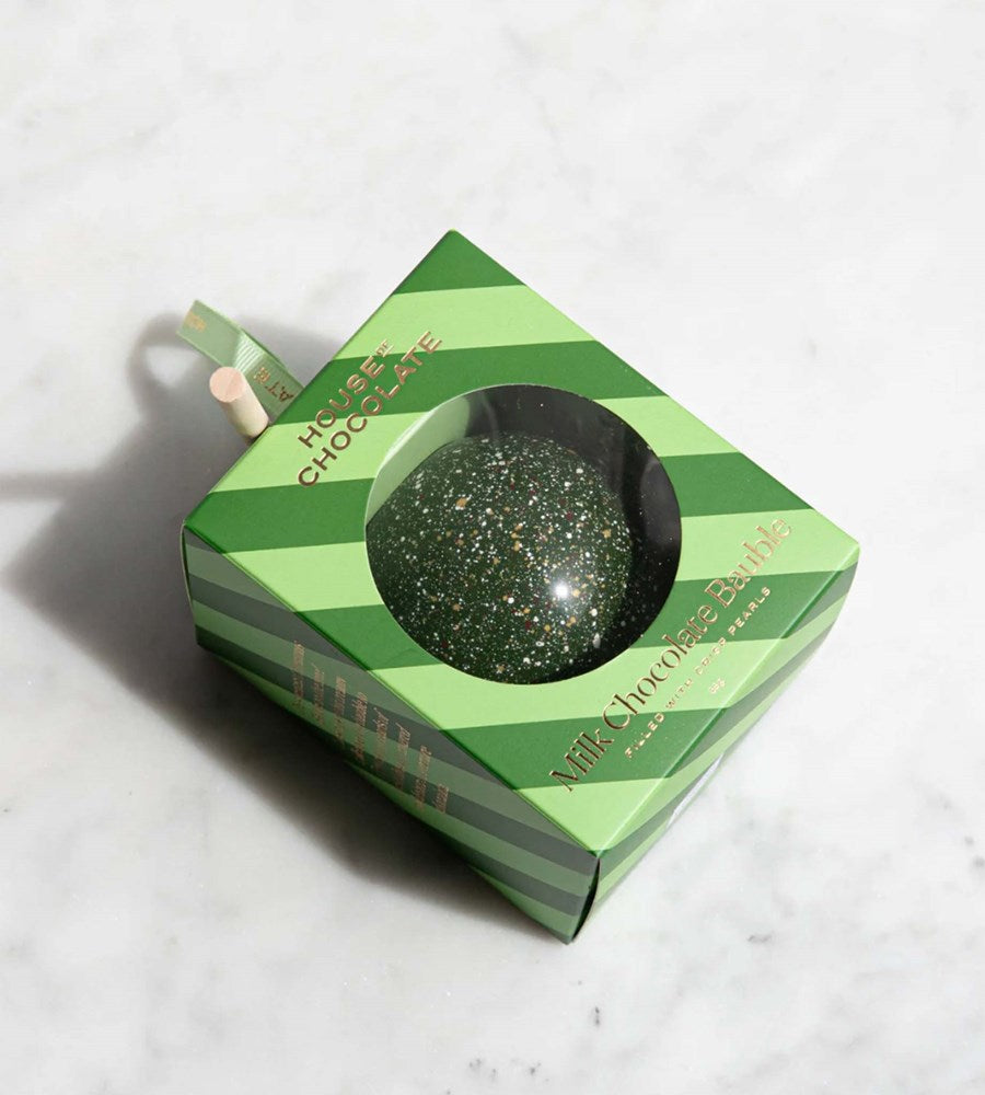 Green chocolate ball in a striped box on a light gray background