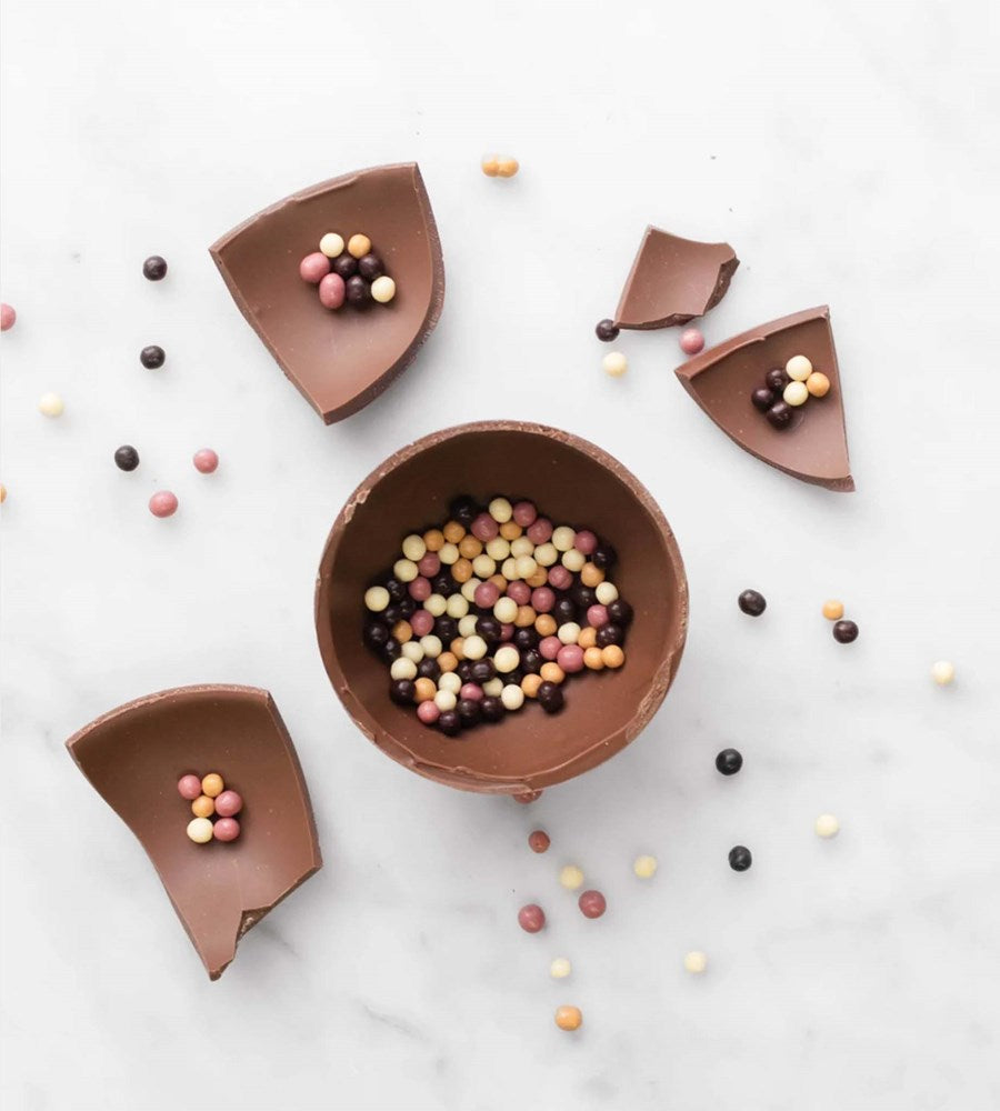 Chocolate bowls filled with colorful candies on a light surface