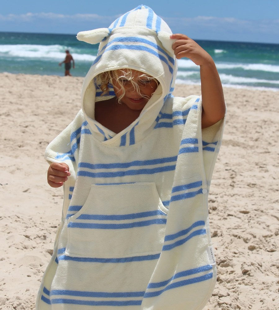 Person wrapped in a blue and white striped towel on a beach