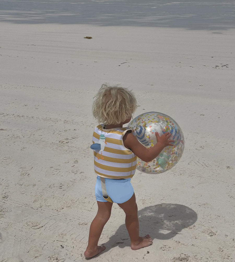 Child holding a beach ball on a sandy beach