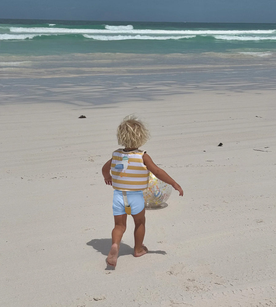 Child walking on a sandy beach with ocean waves in the background