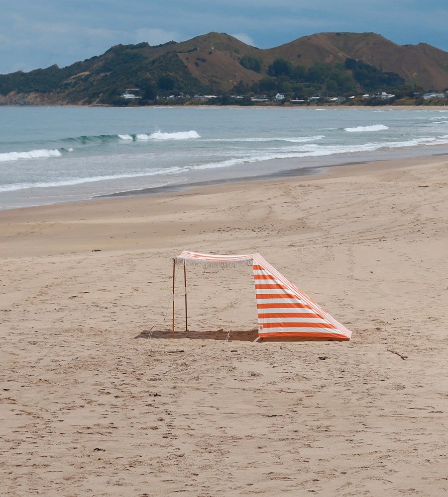 Beach scene with a striped towel on sand and mountains in the background