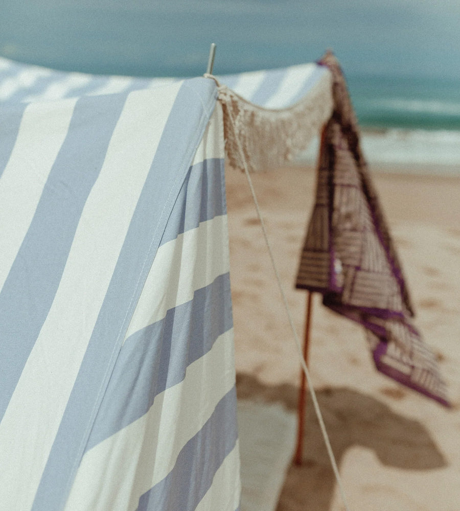 Striped towel and woven basket on a beach with ocean in the background