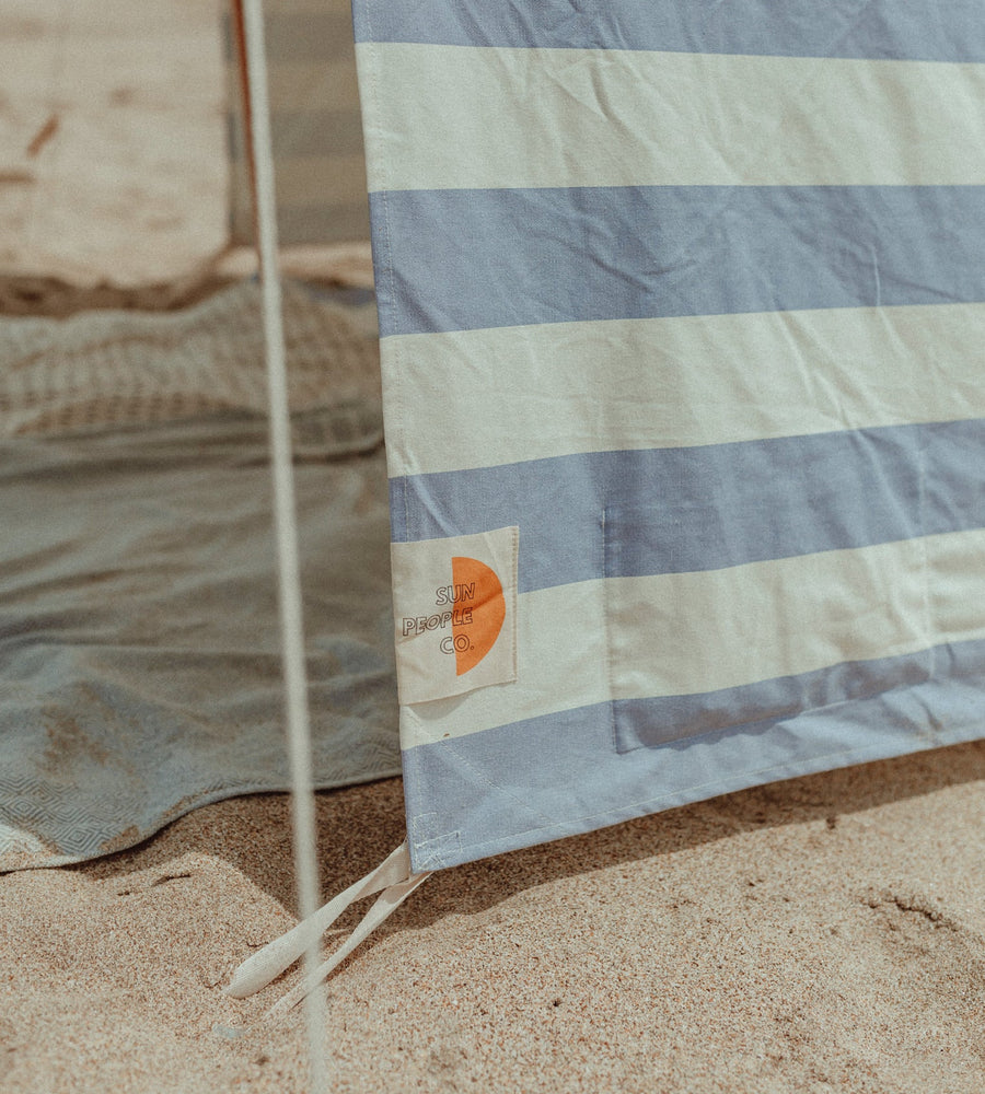 Striped towel with a brand logo on a sandy surface