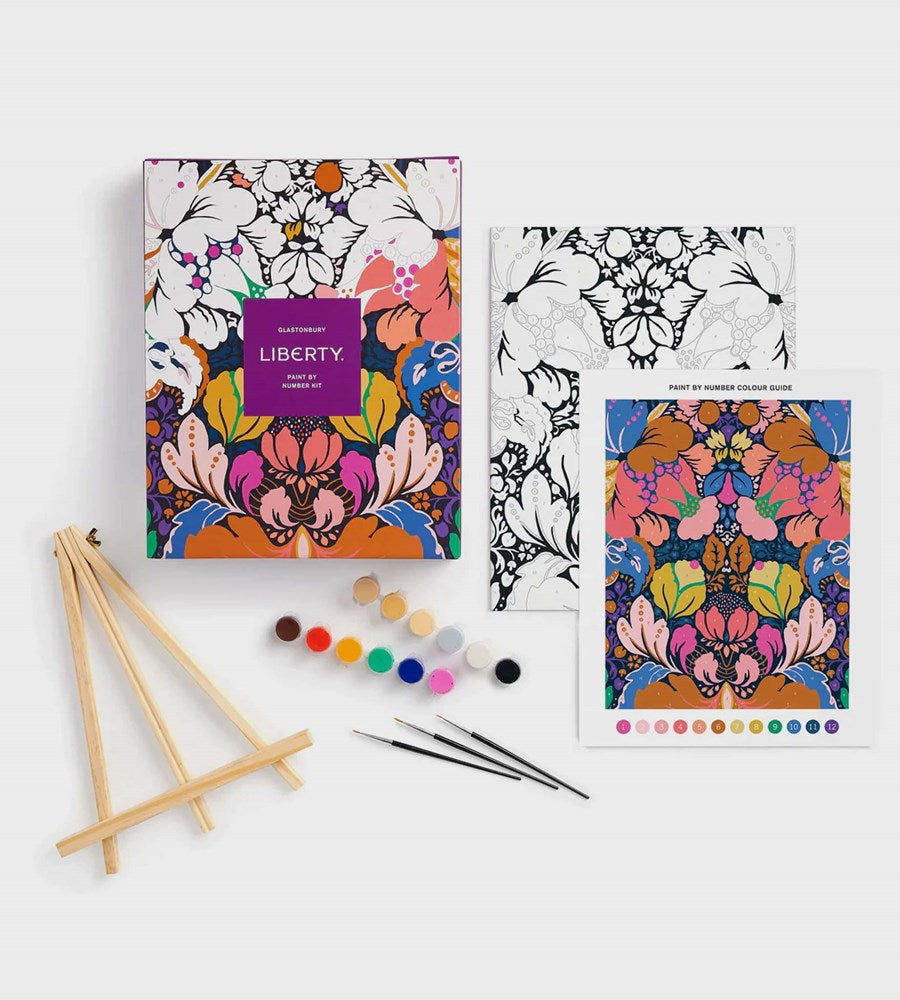 Coloring book set with floral designs, paintbrushes, and paint on a white background