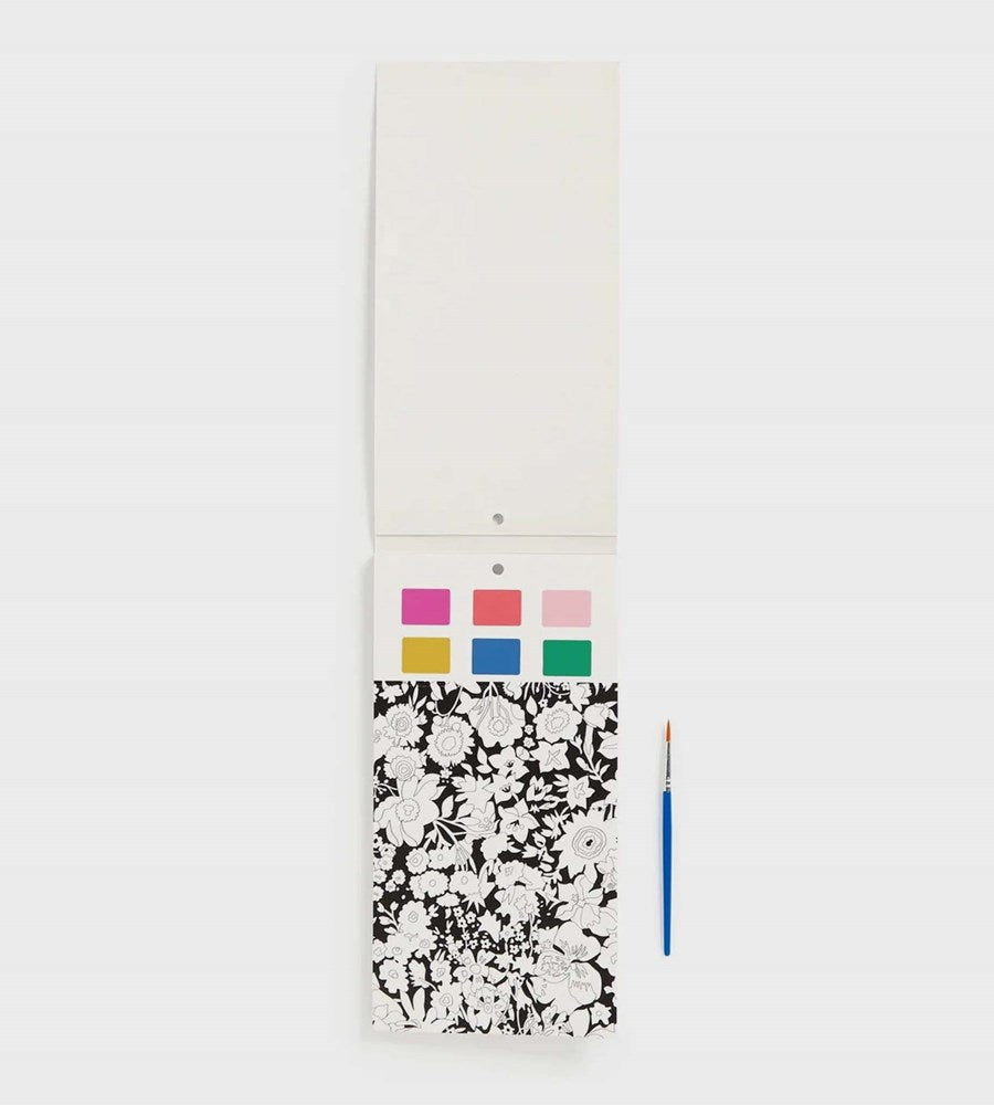 Color swatch book with paint samples and a brush on a white background