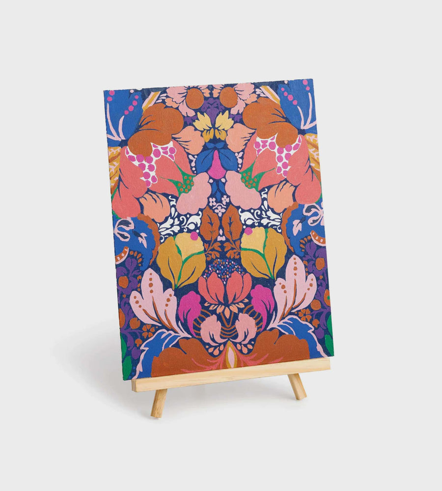Colorful floral patterned fabric on a small wooden easel against a white background
