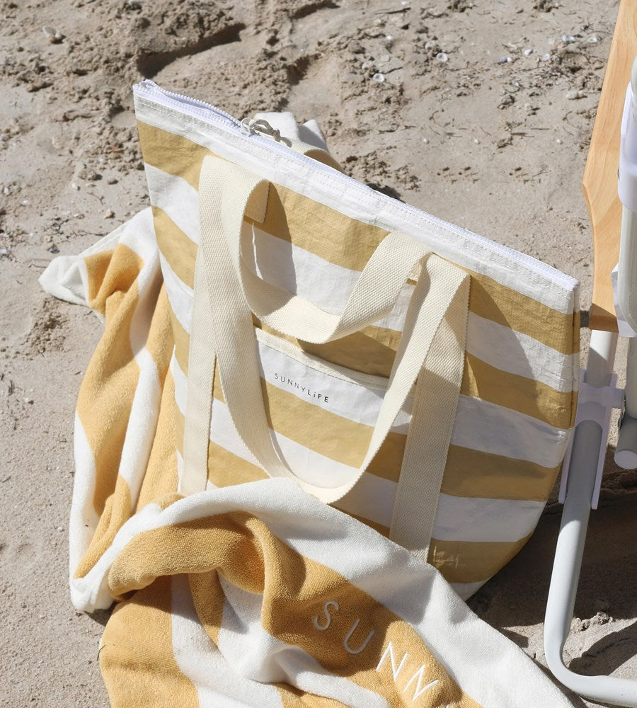 Beach chair with yellow and white striped towel and 'Sunny' text on sand