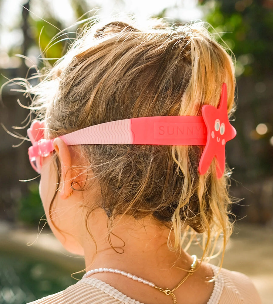 Person wearing a pink headband with star-shaped clips outdoors