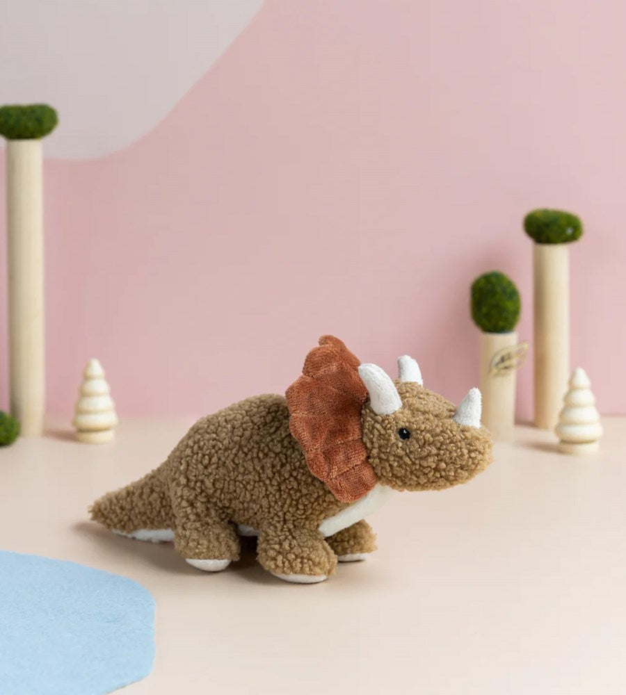Plush dinosaur toy with a pink and beige background