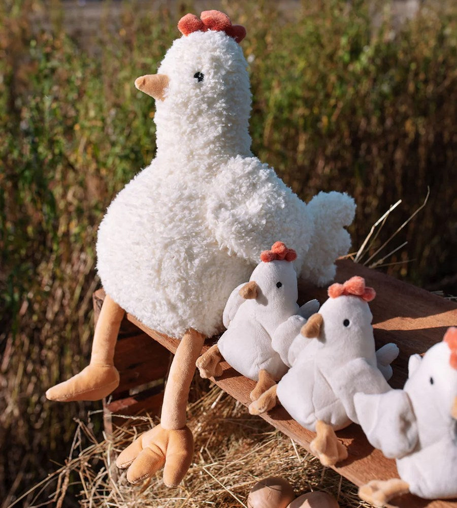 Plush chicken toys on a hay bale with a natural background