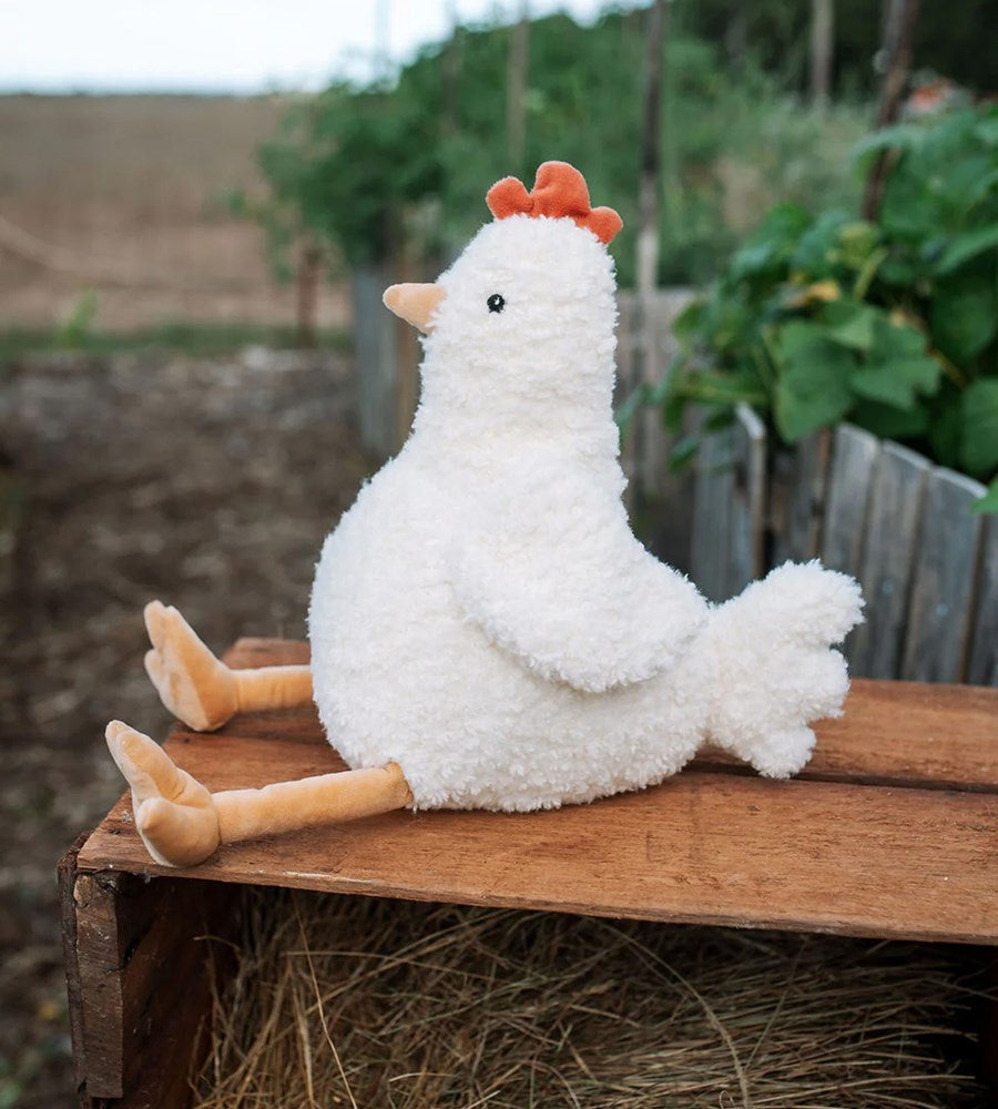 Plush chicken toy on a wooden surface with a natural outdoor background