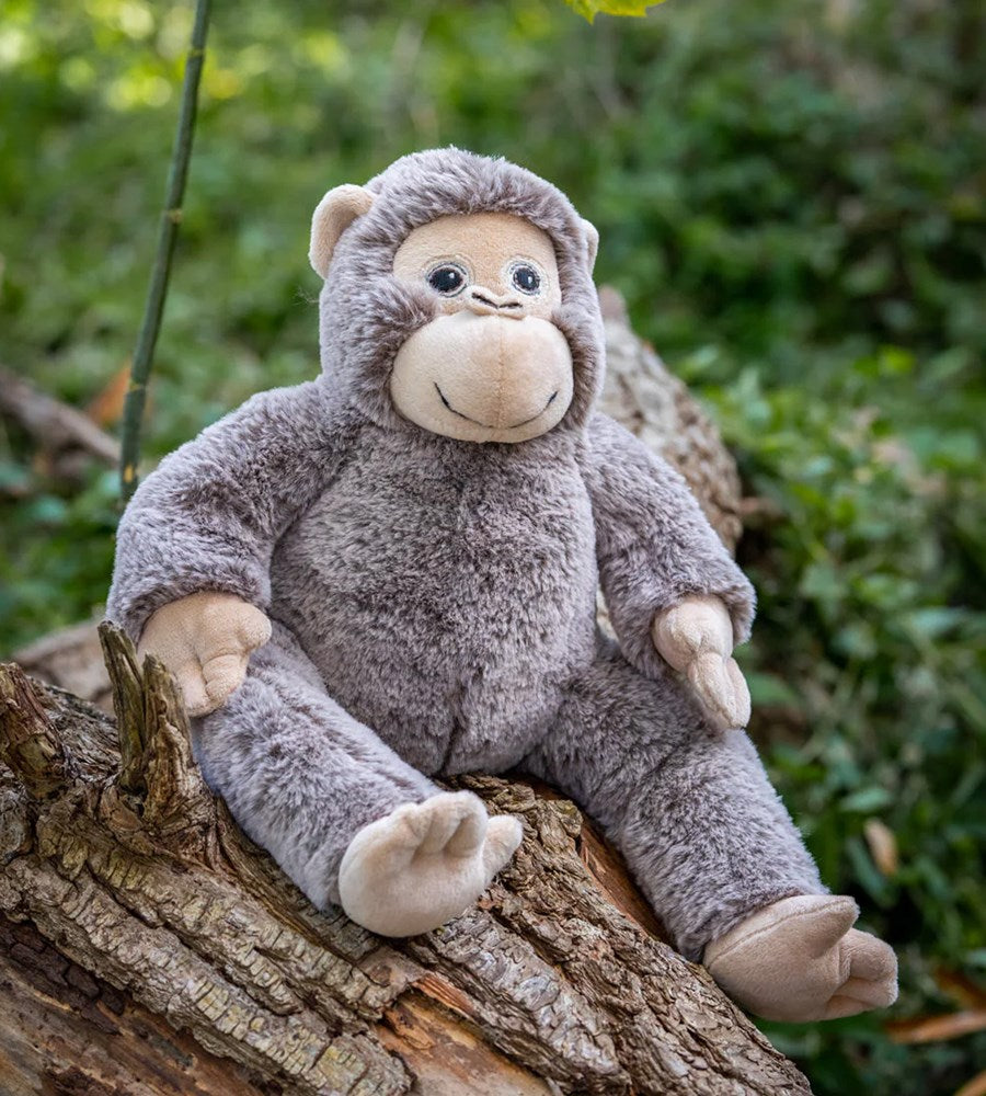 Plush monkey toy sitting on a log with a natural background