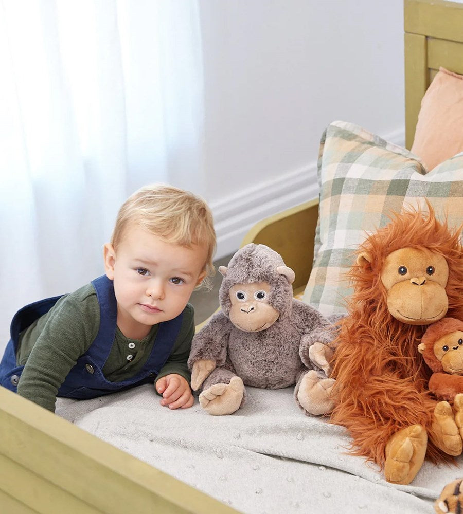 Child with plush toys on a bed in a cozy bedroom