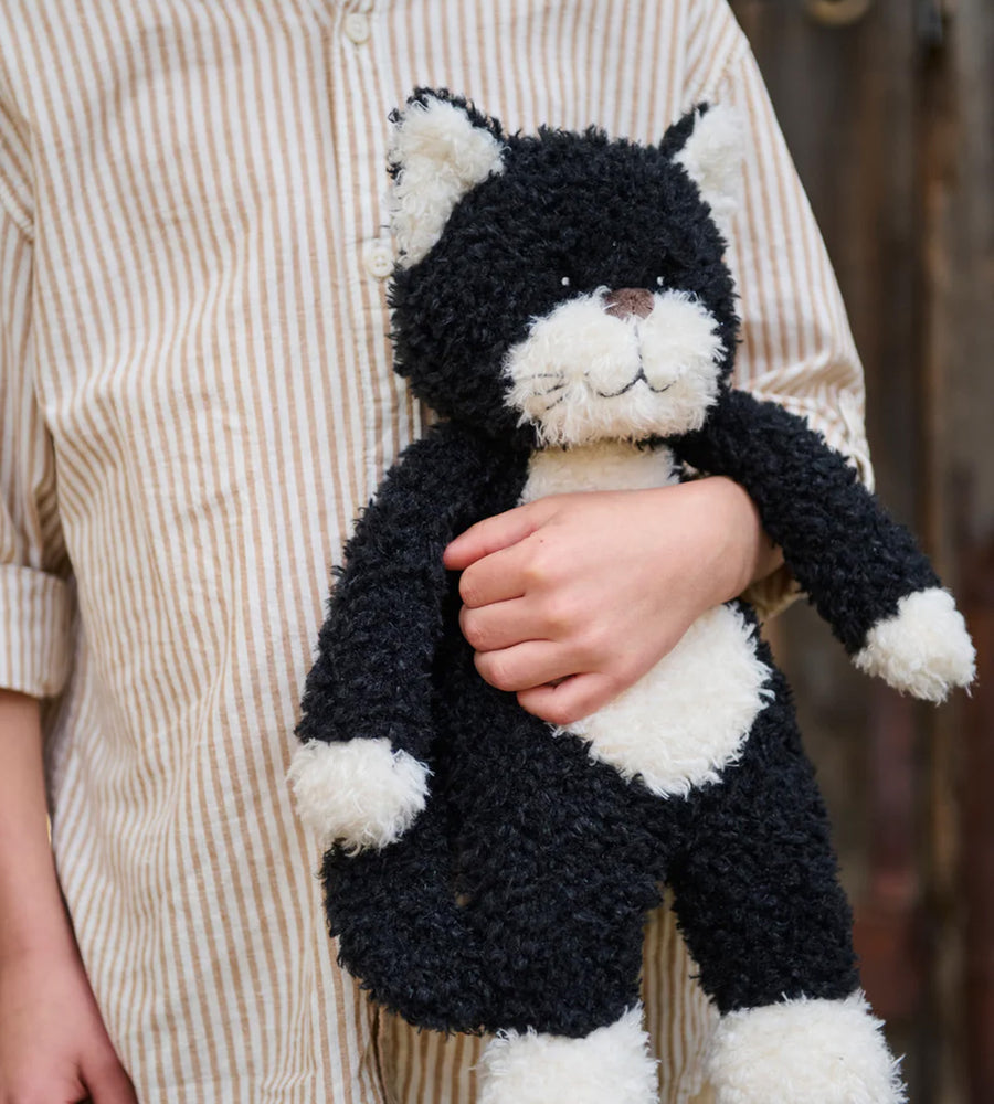 Person holding a black and white plush cat toy