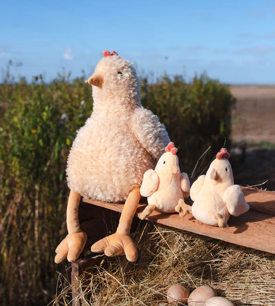 Plush chicken and chicks on a hay bale with a natural background