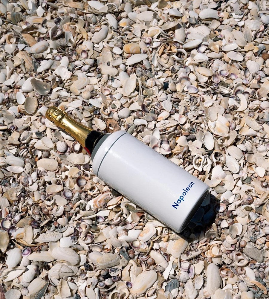 White bottle with gold cap lying on pebbles