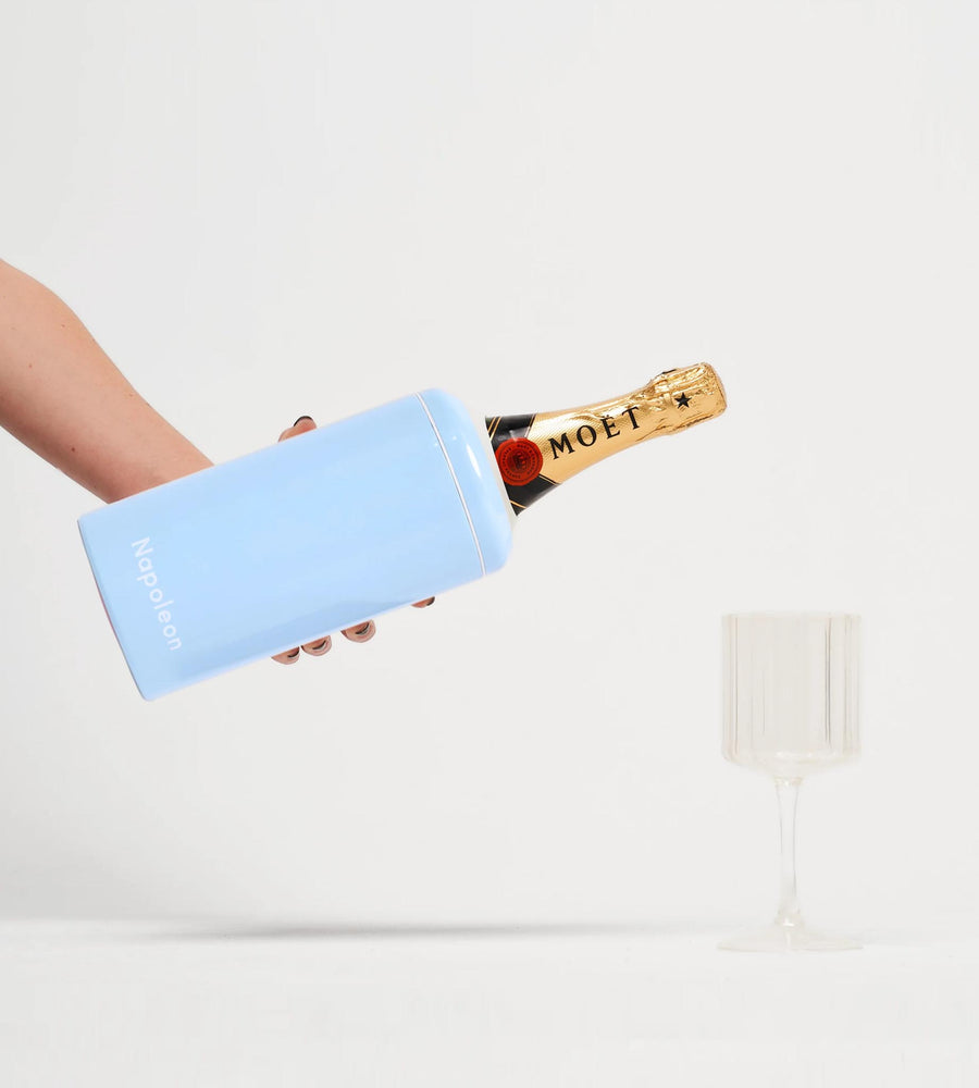 Person holding a champagne bottle with a blue ice pack against a white background