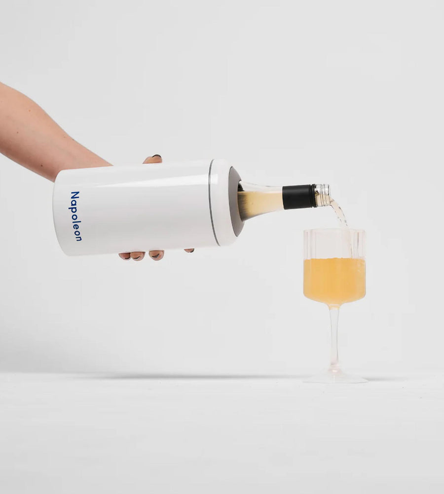 White bottle with a black cap being poured into a glass, on a white background