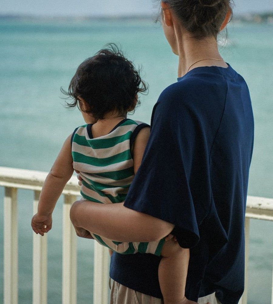 Person holding a child by a body of water