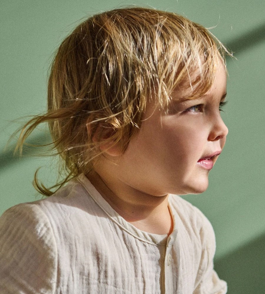 Young child with light brown hair against a green background