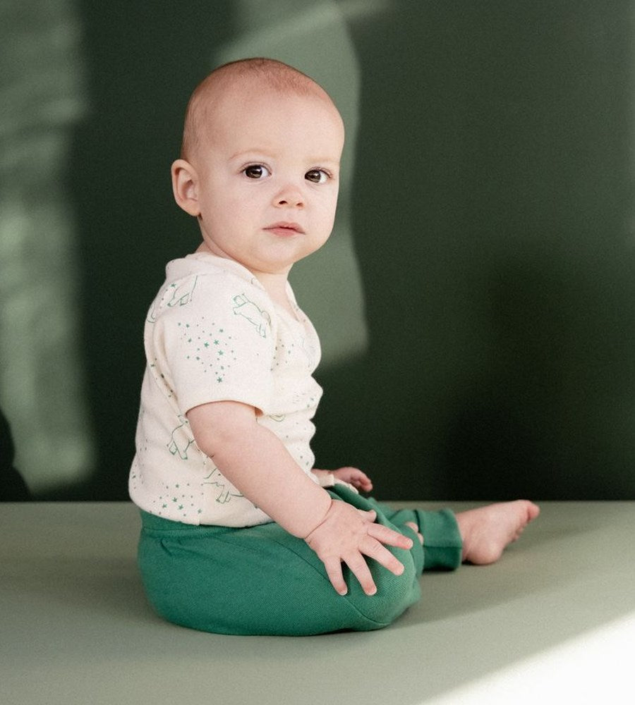 Baby sitting on a surface with a blurred green background