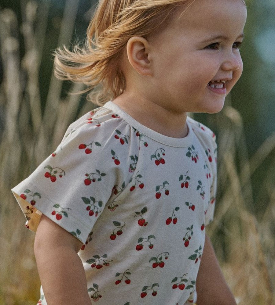 Child wearing a shirt with cherry pattern in an outdoor setting
