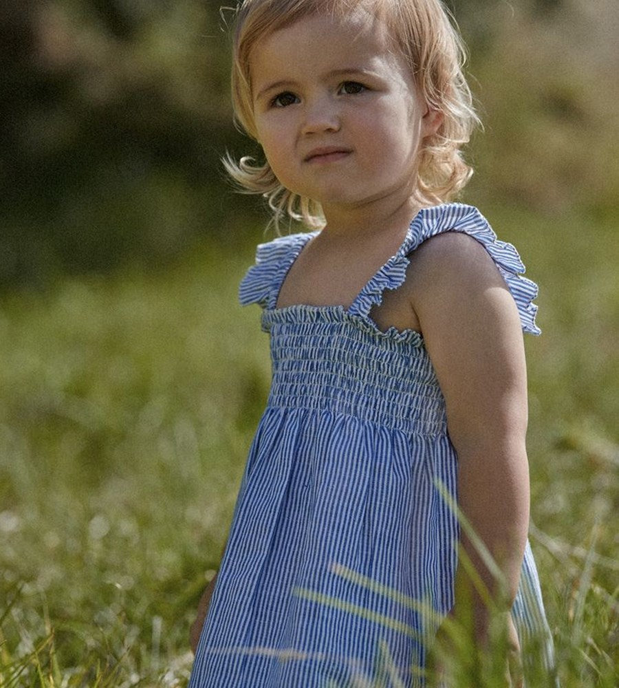 Young girl in a blue dress standing in a grassy field