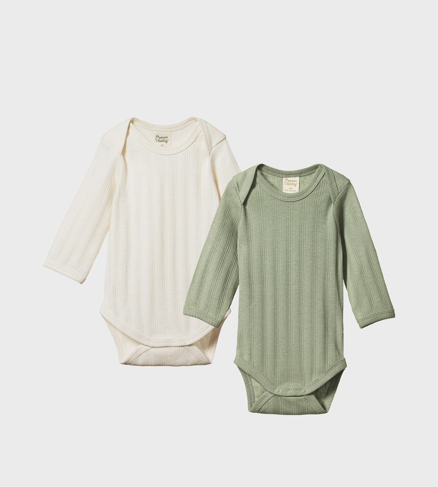 Two baby bodysuits, one white and one green, on a light gray background.