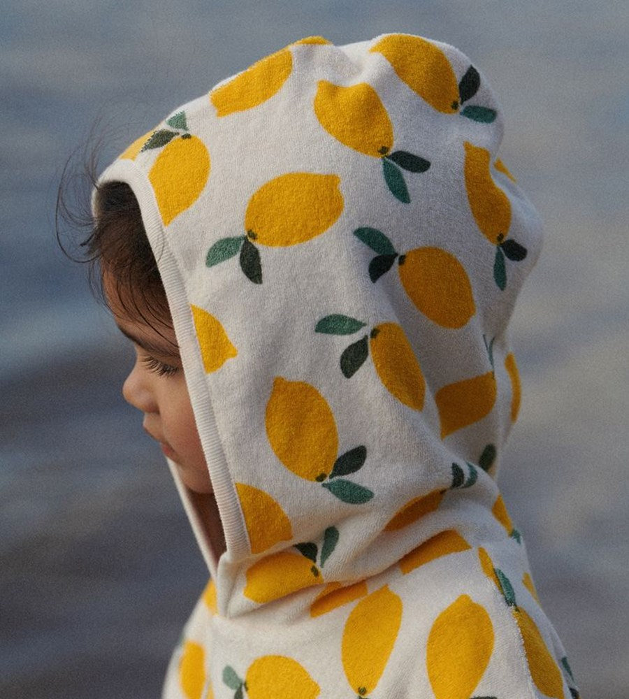 Child wearing a hoodie with lemon pattern against a blurred natural background