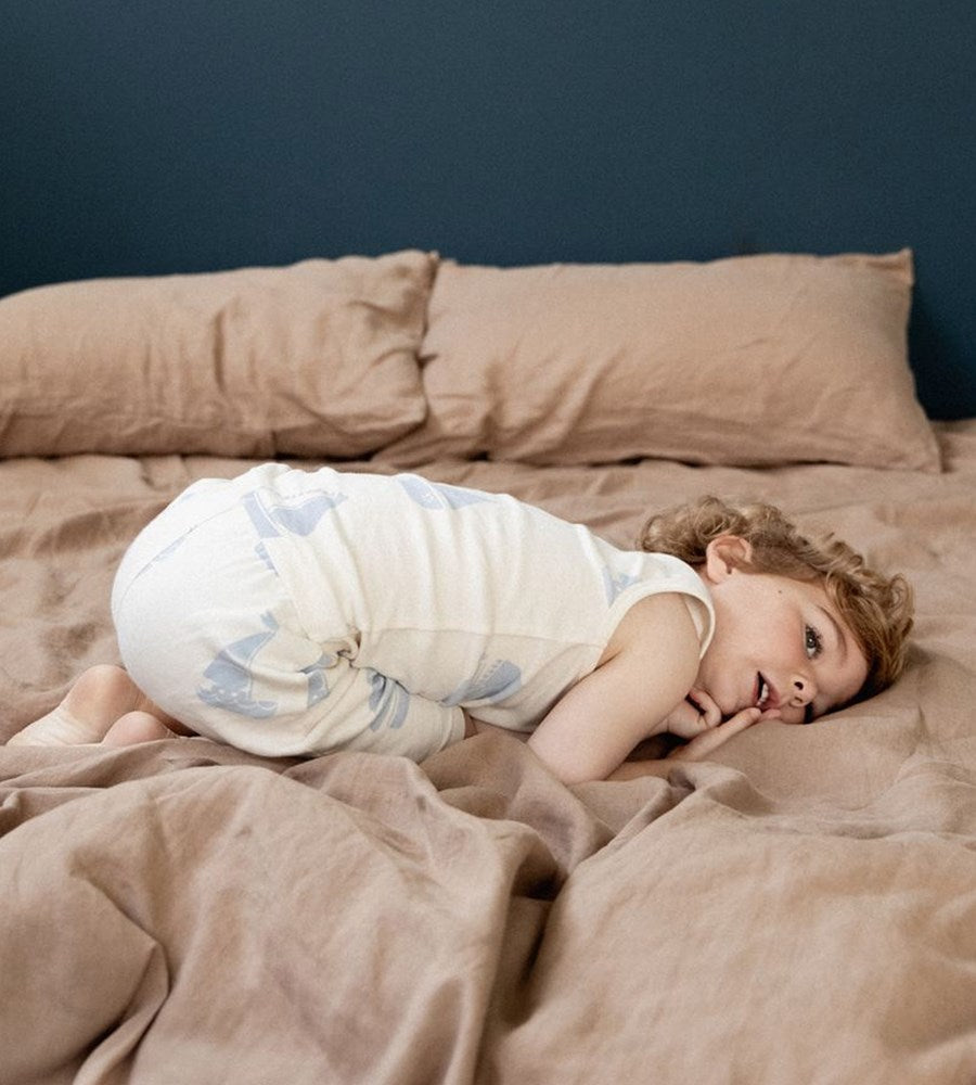 Child lying on a bed with brown bedding and pillows